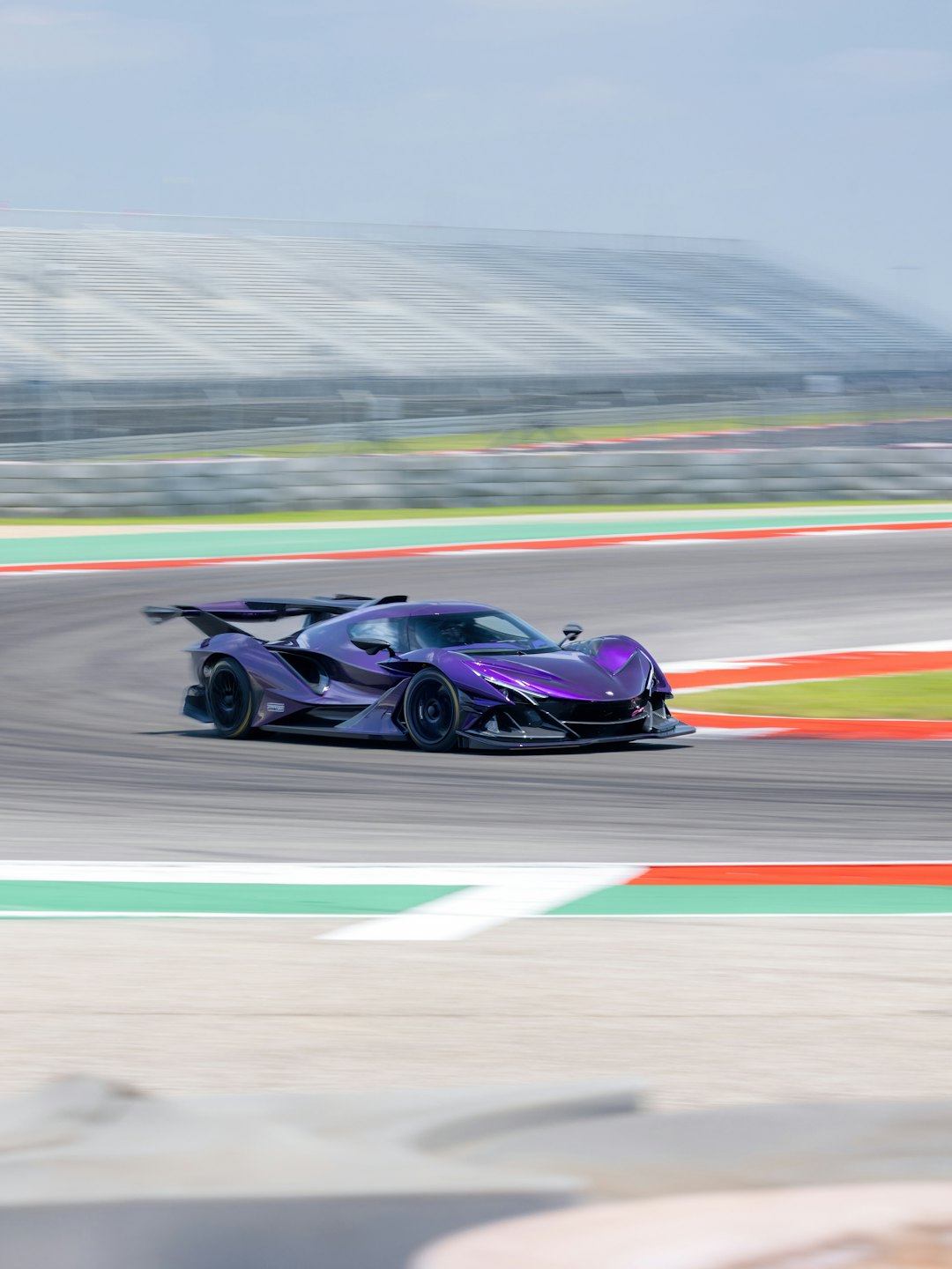 A purple sports car speeds around a race track.