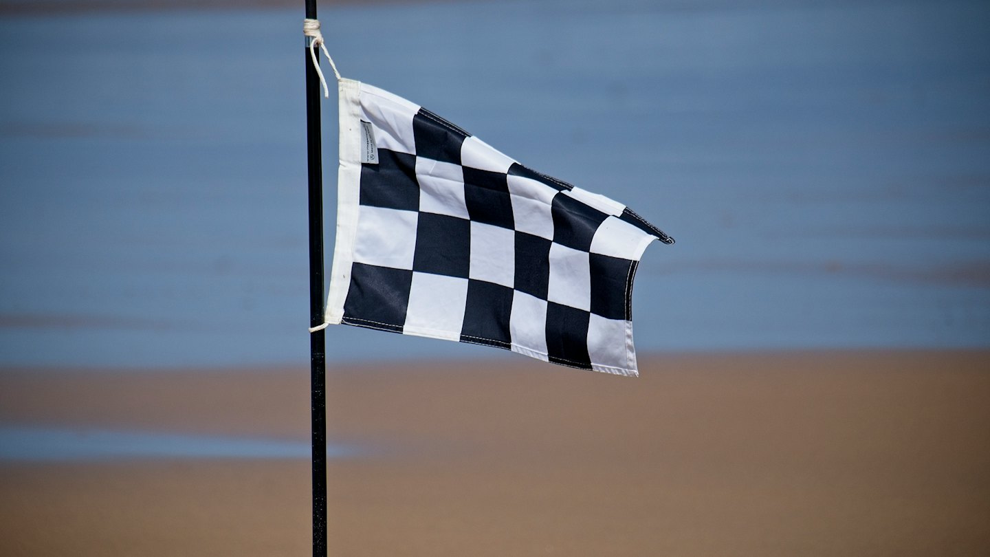Black and white checkered flag waving on a pole.