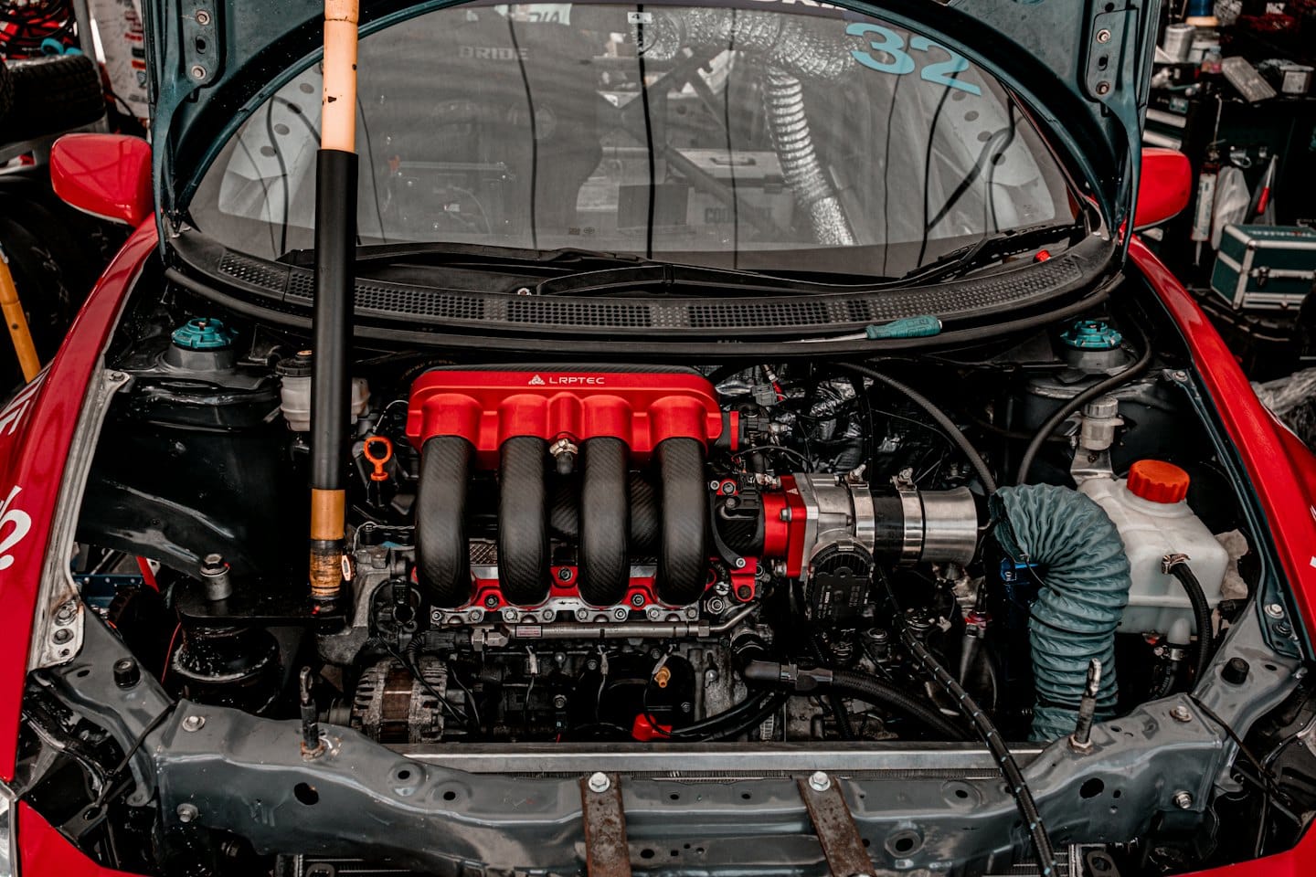 High performance car engine with a red cover in a workshop.