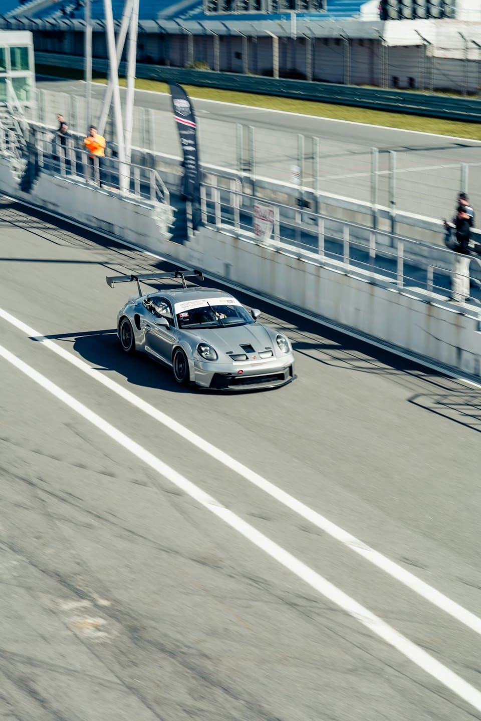 A silver race car speeds along a paved track.