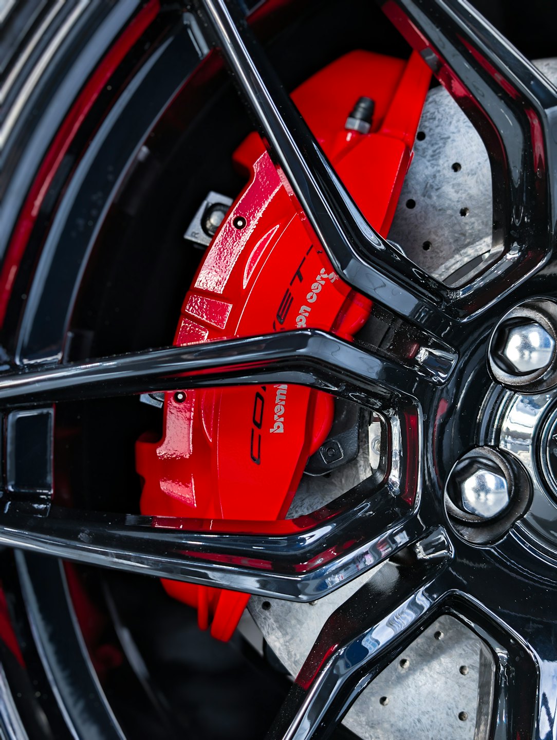 Black multi-spoke rim with a red brake caliper.